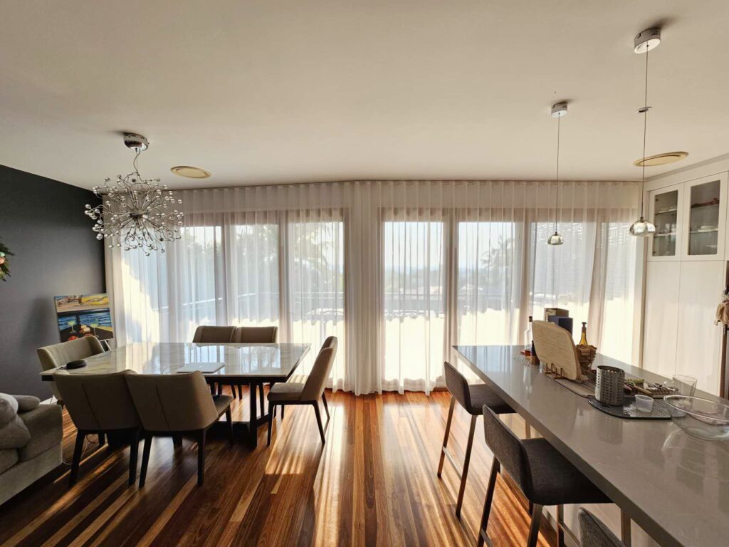 S-fold transparent sheers adorning large windows in a spacious living room.
