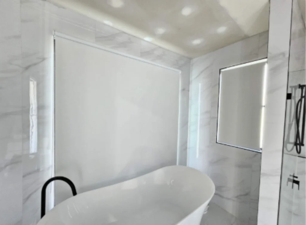 2 white blockout roller blinds installed in bathroom